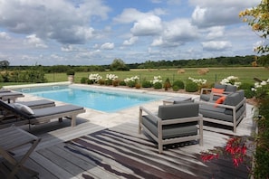 A swimming pool with lounge chairs and a wooden deck.