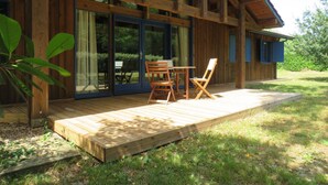 Une cabane en bois avec une terrasse, une table et des chaises.
