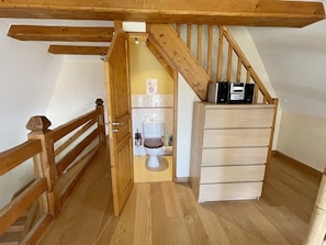 Cozy attic-style bedroom with a single bed, wooden nightstand, and wardrobe.