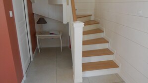 A staircase with wooden steps and white walls, leading to a landing with a small table and a lamp.