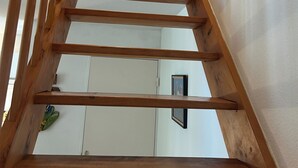 Un escalier en bois menant à un palier avec un mur blanc et une porte.