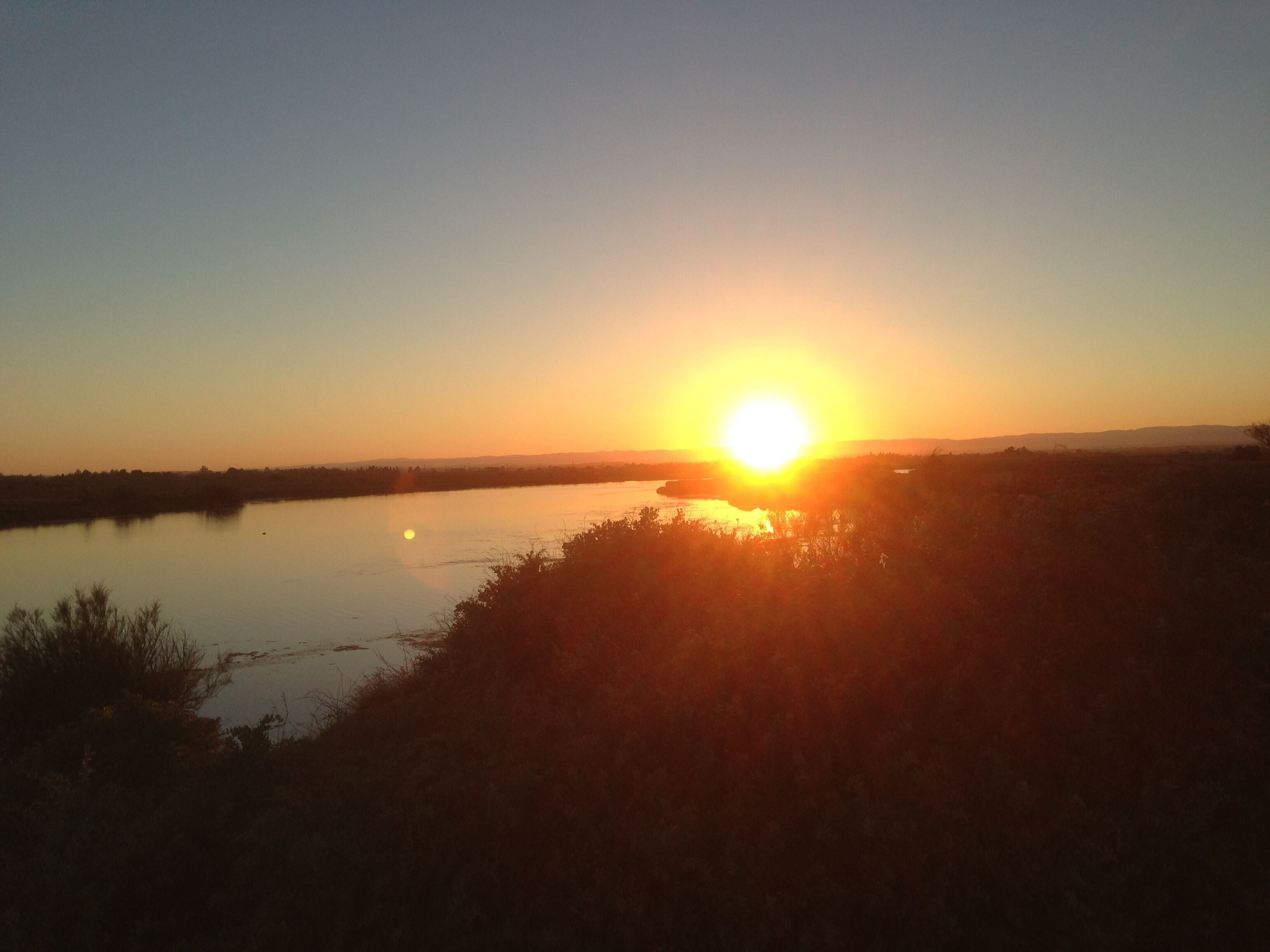A sunset over a calm body of water with a distant horizon.