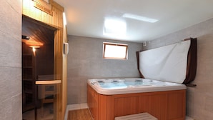 Un bagno moderno con una vasca da bagno in legno, un piccolo sgabello e una zona doccia con pareti in vetro.