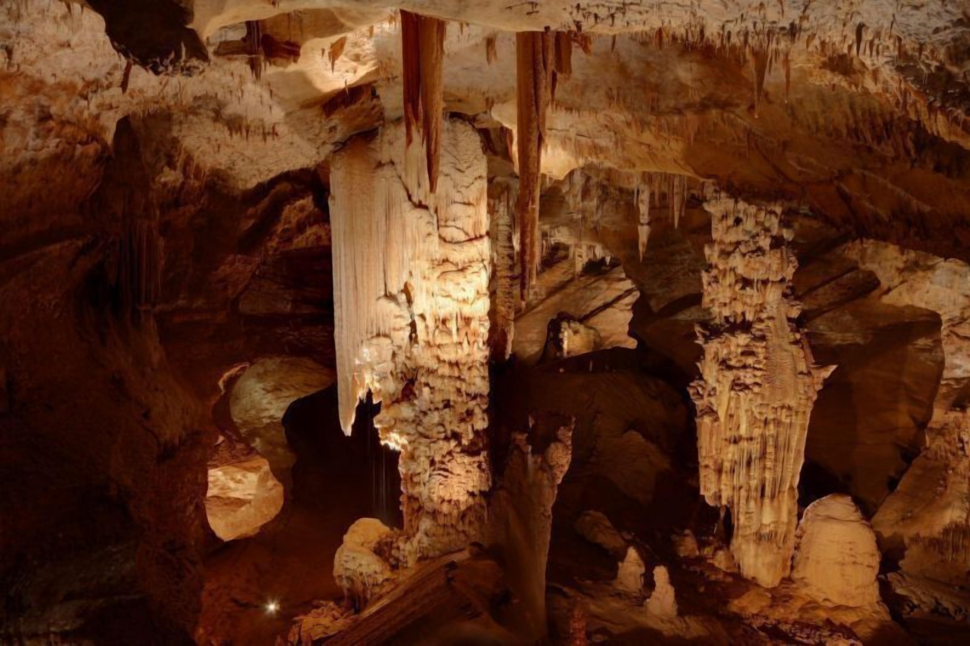 Une grotte ornée de stalactites et de stalagmites, éclairée par un système d’éclairage artificiel.