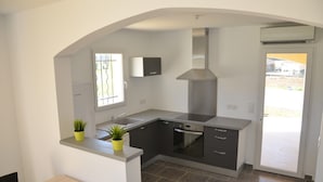 A modern kitchen with a built-in oven, a stainless steel range hood, and a window with a view of the outside.