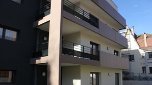 Un edificio residencial de varios pisos con balcones, ventanas amplias y techo plano.