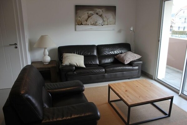 Ein Wohnzimmer mit einer schwarzen Ledersofa, einem Holztisch und einem Gemälde von Eisbären an der Wand.