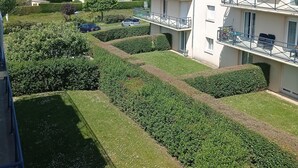 Ein mehrstöckiges Wohngebäude mit Balkonen, einem gepflegten Garten und Blick auf das Meer.