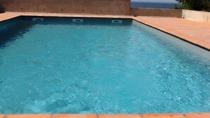 Une piscine rectangulaire à l’eau d’un bleu limpide, entourée d’une terrasse carrelée.