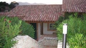Un bâtiment avec un toit recouvert de tuiles rouges, des murs en pierre et un chemin de pierre menant à une porte en bois.