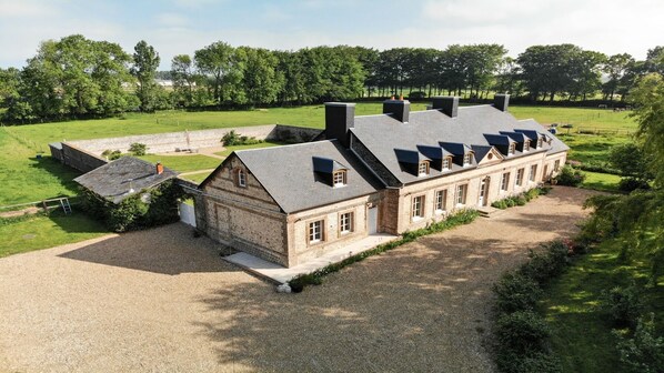 Un grand bâtiment d’un seul étage, doté d’une toiture symétrique, entouré d’une allée gravillonnée et d’un champ d’herbe.