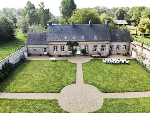 Un grand bâtiment en pierre à deux étages, doté d’une façade symétrique, de nombreuses fenêtres et d’une cour centrale avec un chemin de gravier.
