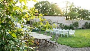 An outdoor seating area with round tables and chairs, surrounded by a stone wall and greenery. - Manoir de 400 sqf near the see, Billard, Babyfoot & Sauna. Pets welcome ! (Sassetot-Le-Mauconduit)