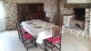 A dining area with a stone wall, a wooden cabinet, and a fireplace. - 2 * house for 6 people direct access to the sea (Bouin)