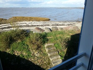 A coastal view with a rocky shoreline, a grassy area, and a distant cityscape. - 2 * house for 6 people direct access to the sea (Bouin)