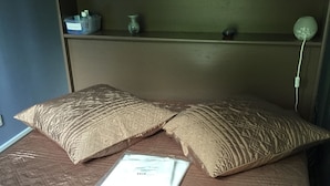 A bed with a patterned bedspread, two pillows, and a white envelope on the bed. - Apartment in luxury residence downtown (Cauterets)