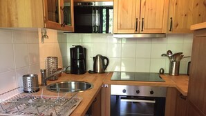 A kitchen with wooden cabinets, a stainless steel sink, a coffee maker, and an oven. - Apartment in luxury residence downtown (Cauterets)