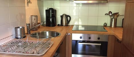 A kitchen with wooden cabinets, a stainless steel sink, a coffee maker, and an oven.