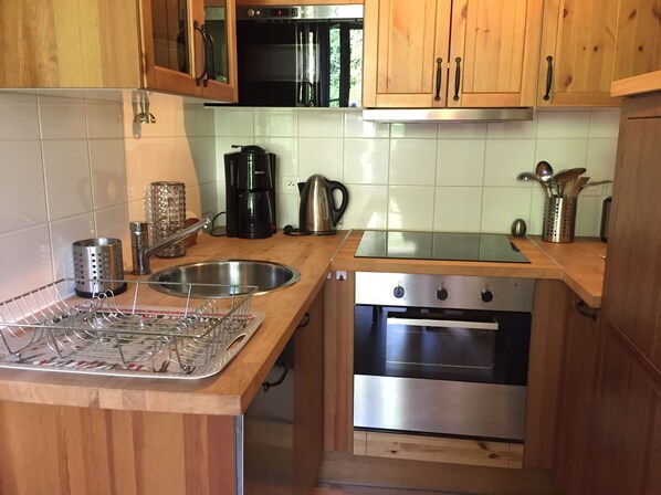 A kitchen with wooden cabinets, a stainless steel sink, a coffee maker, and an oven.