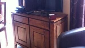 Ein Wohnzimmer mit einem Holzkabinett, einem Fernseher darauf und einem dunkelgrauen Sofa.