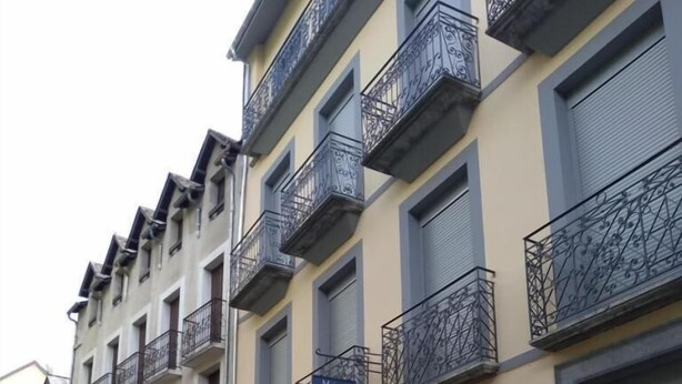 A row of multi-story buildings with balconies, a sign indicating a hotel, and a street in front. - Apartment in luxury residence downtown (Cauterets)