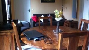 A round wooden dining table with chairs, a laptop, and a vase with flowers. - Apartment in luxury residence downtown (Cauterets)