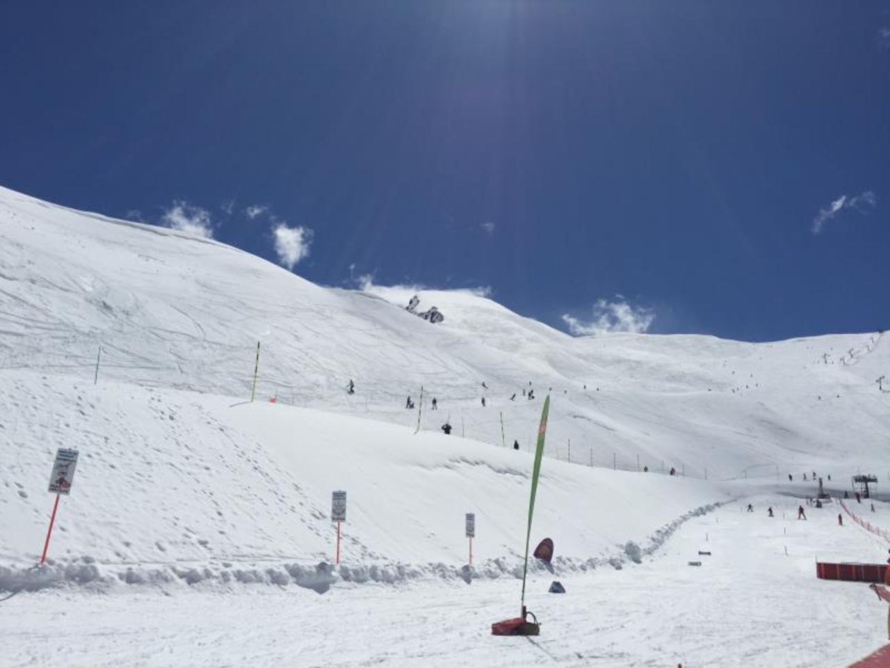 A snowy ski slope with marked trails and a clear blue sky.