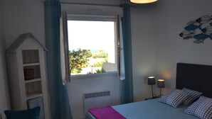A bedroom with a bed, a window with curtains, a bedside table with lamps, and a wall decoration.