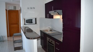 A compact kitchen with a microwave, sink, and a built-in oven.