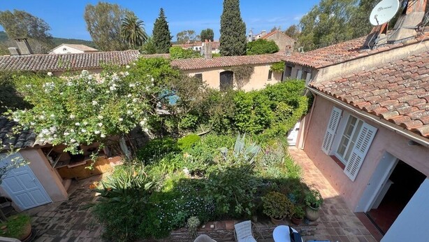 Ein Innenhof mit Terrassenbereich, Gartenmöbeln und einem Garten.