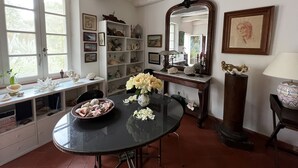 Ein Essbereich mit einem runden Tisch, Stühlen, einer Blumenvase, einem Regal mit Dekoration und einem großen Spiegel.