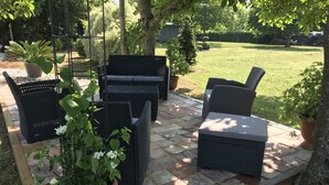 An outdoor patio with wicker furniture, potted plants, and a brick floor. - CHARMING FAMILY HOME (Baigts)