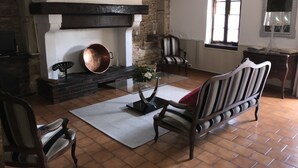 A living room with a fireplace, a coffee table, striped chairs, and a tiled floor. - CHARMING FAMILY HOME (Baigts)