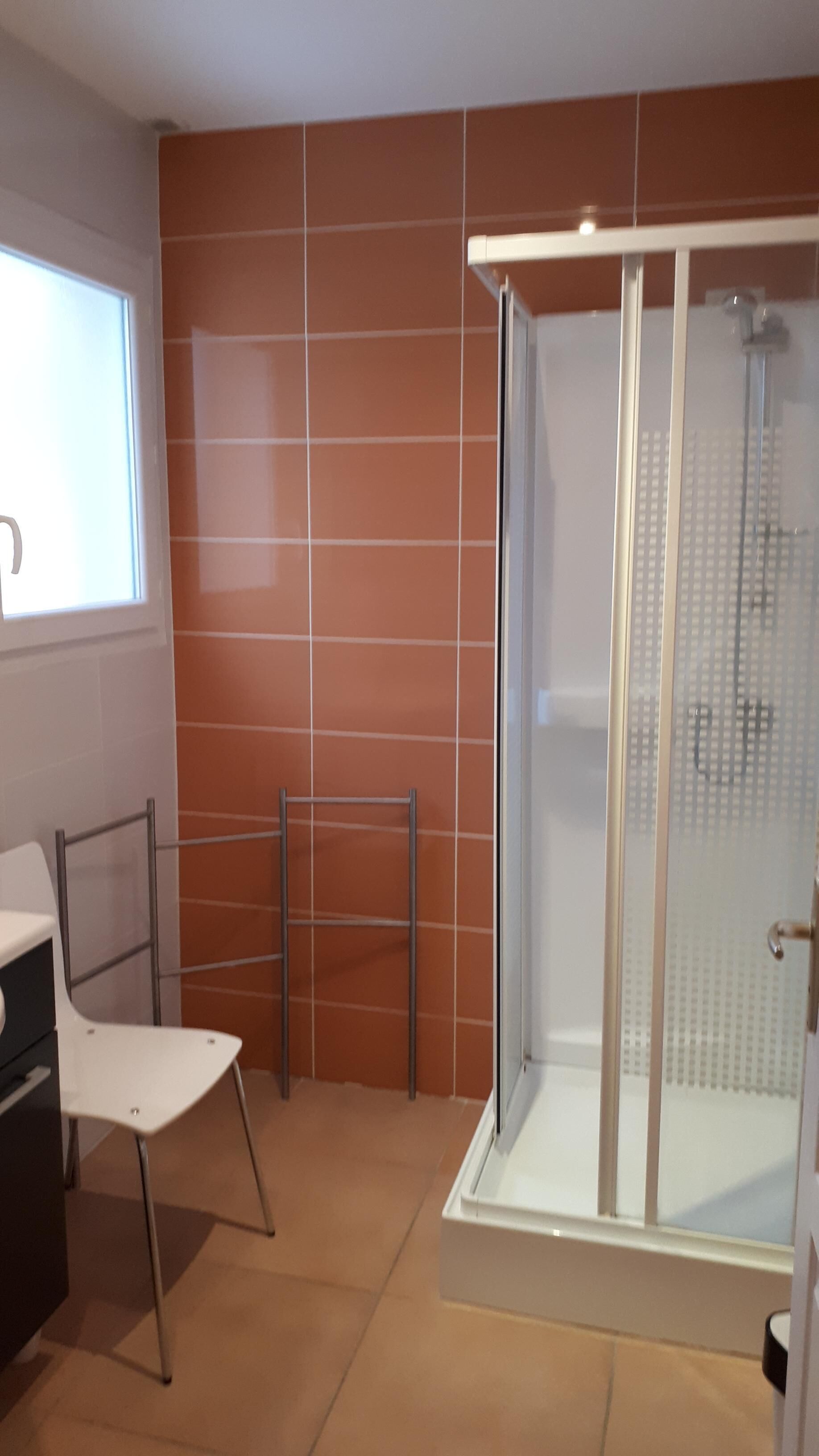 Une salle de bain avec une douche, une chaise et un lavabo.