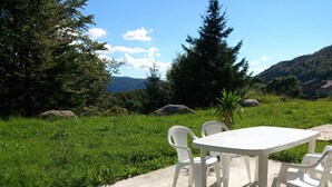 A concrete patio with a white table and four chairs, surrounded by lush greenery and trees. - TOP-OF-THE-RANGE DUPLEX 95 m2 GARDEN GROUND TO 1.8 KM SKI STATION (Bellefontaine)