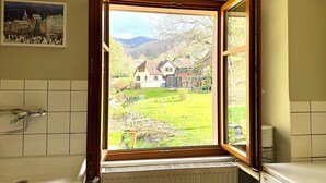 A bathroom with a window view of a house and a garden. - Cottage in a quiet and green ski trails near hiking (Maisonsgoutte)