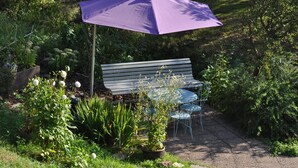 A garden with a bench, a purple umbrella, and potted plants. - Cottage in a quiet and green ski trails near hiking (Maisonsgoutte)