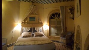 A bedroom with a bed, a chair, a window, and a wall-mounted picture. - Lotus-Essaouira .com SEA VIEW - PRIVATE TERRACE - near BEACH (ESSAOUIRA)