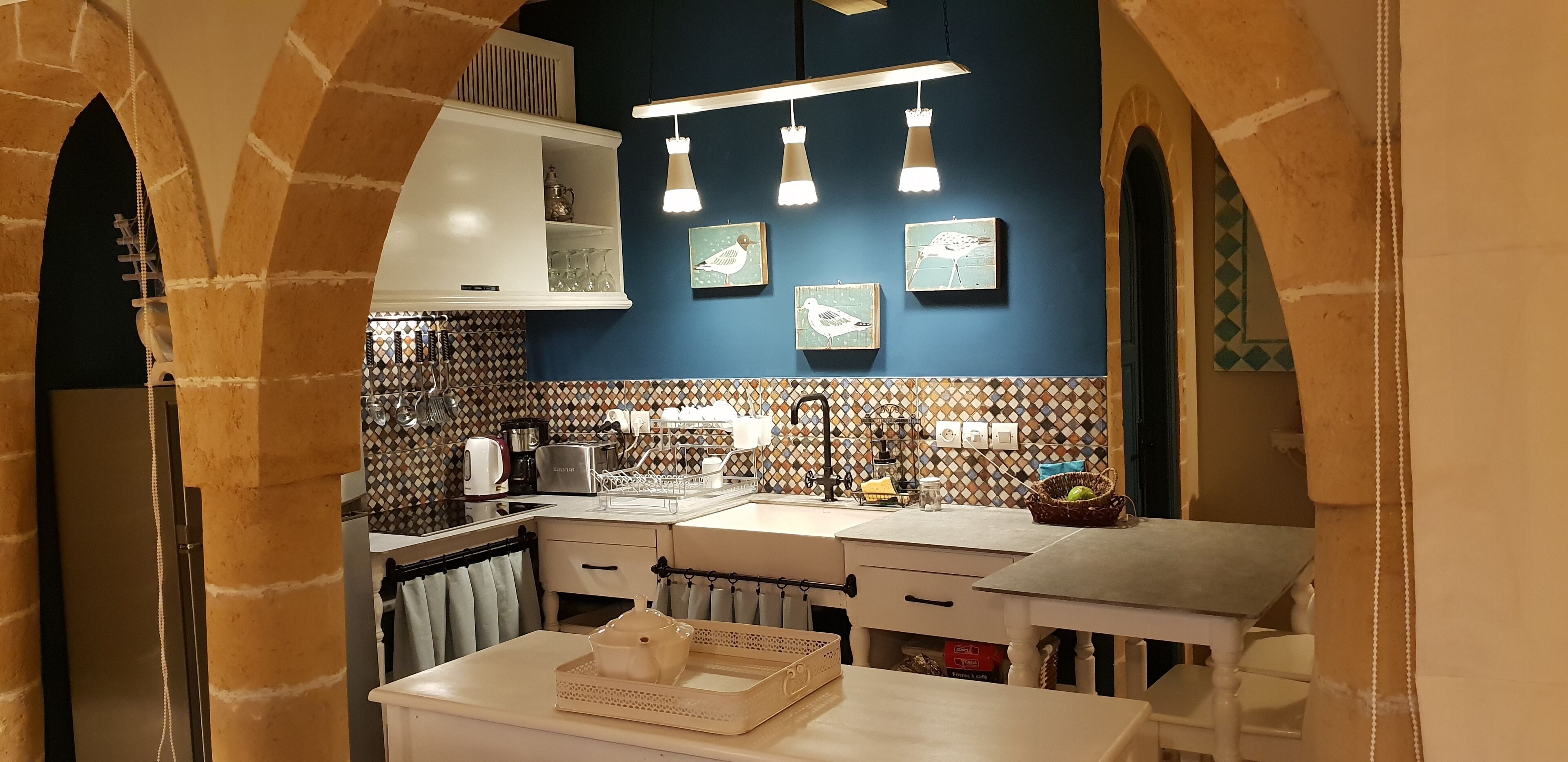 A kitchen with a modern design, featuring a white countertop, a built-in oven, and a hanging light fixture.