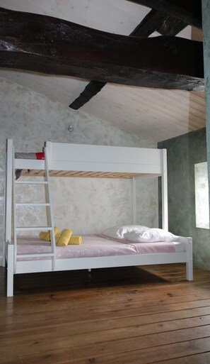 Ein Stockbett mit einer Leiter, einem Fenster und Holzdielen.