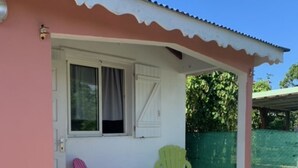 A small house with a pink exterior, a white door, and a covered porch area. - Holiday rental in Petit-Canal (Guadeloupe) (PETIT-CANAL)