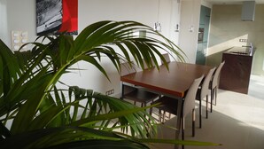 Una cocina moderna con comedor, que incluye una mesa de madera, sillas y una planta grande en maceta.