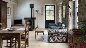 Una sala de estar acogedora con techo alto, chimenea, televisor y comedor con mesa y sillas de madera.