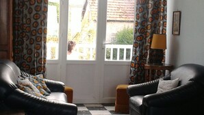 A living room with two black leather sofas, patterned curtains, a checkered floor, and a small table with a lamp.