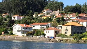 Une ville côtière avec des bâtiments construits sur une colline, un front de mer et un ciel dégagé.