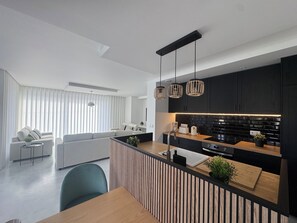 A modern kitchen with a central island, black cabinetry, and pendant lighting.