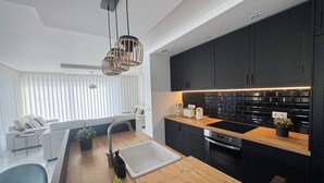 Une cuisine moderne avec des meubles de couleur sombre, un plan de travail en bois et un four encastré.