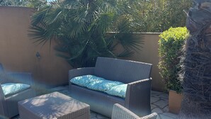 Un espace patio aménagé avec des meubles en osier et un palmier.