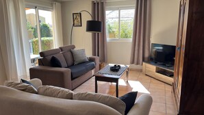 Un salon avec un canapé, une table basse, un téléviseur et une lampe.