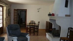 Un salon avec une cheminée, une table à manger avec des chaises et un grand fauteuil.